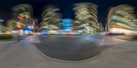 a city view with the blurred streets and traffic lights at night time as seen from inside a fisheye lens