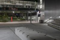 steps leading down to large building at night on sidewalk in dark courtyard area with glass railings