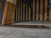 a wooden floor outside a building at night with dark lights on and dark wood paneling