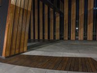 a wooden floor outside a building at night with dark lights on and dark wood paneling