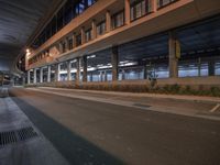 empty parking garage with car parked at an exit ramp at night time with a light reflecting on the pavement