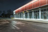 an empty parking lot with a sign pointing at a red and yellow building at night