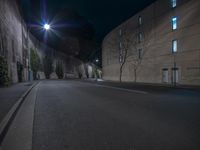 a car sits parked on the side of an empty street at night as a person walks by