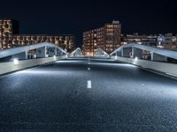 a highway with several bridges over it at night time with tall buildings in the background