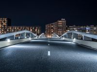 a highway with several bridges over it at night time with tall buildings in the background