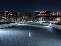 a highway with several bridges over it at night time with tall buildings in the background