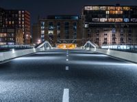 a highway with several bridges over it at night time with tall buildings in the background