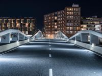 a highway with several bridges over it at night time with tall buildings in the background