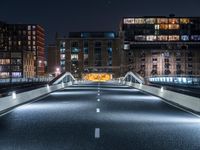 a highway with several bridges over it at night time with tall buildings in the background