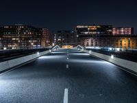 a highway with several bridges over it at night time with tall buildings in the background