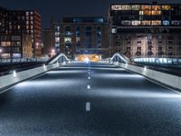 a highway with several bridges over it at night time with tall buildings in the background