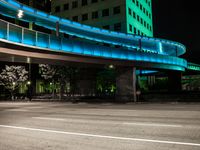 a walkway near a building with green lights and blue lights at night in a city