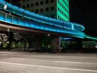 a walkway near a building with green lights and blue lights at night in a city