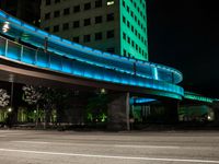 a walkway near a building with green lights and blue lights at night in a city