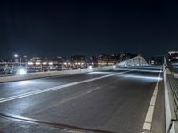 a highway and some tall buildings in the night sky with a person riding a scooter at the end of a ramp