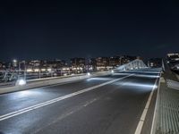 a highway and some tall buildings in the night sky with a person riding a scooter at the end of a ramp