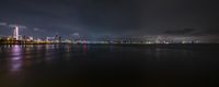 an illuminated city across the water from a beach at night time, illuminated by street lights