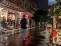 rain falls onto the street as it passes by a building on a rainy night in tokyo