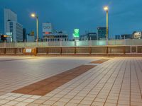 people standing on a subway platform with many buildings in the background at night light in tokyo