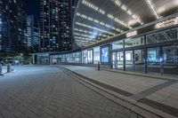 a night scene of the sidewalk next to the building and sidewalk near it in the city