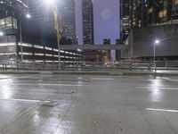 an empty street near several tall buildings at night time in the city with a sky background