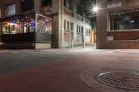 a night time scene with a street intersection with street lights in the background and a manhole