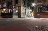 a night time scene with a street intersection with street lights in the background and a manhole