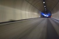 a long tunnel that leads into the distance with people inside and one is driving down the street