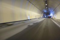 a long tunnel that leads into the distance with people inside and one is driving down the street