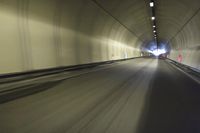 a long tunnel that leads into the distance with people inside and one is driving down the street