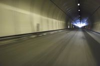 a long tunnel that leads into the distance with people inside and one is driving down the street