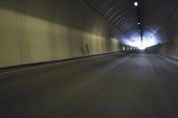 a long tunnel that leads into the distance with people inside and one is driving down the street