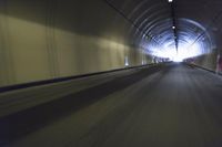 a long tunnel that leads into the distance with people inside and one is driving down the street