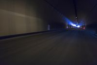 a long tunnel that leads into the distance with people inside and one is driving down the street
