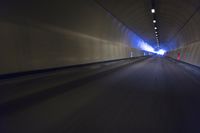 a long tunnel that leads into the distance with people inside and one is driving down the street