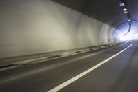 a long tunnel that leads into the distance with people inside and one is driving down the street