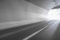 a long tunnel that leads into the distance with people inside and one is driving down the street