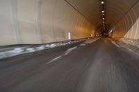 a long tunnel that leads into the distance with people inside and one is driving down the street