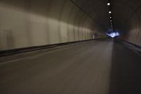 a long tunnel that leads into the distance with people inside and one is driving down the street