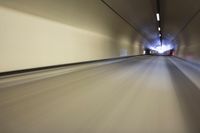 a long tunnel that leads into the distance with people inside and one is driving down the street
