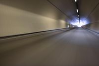 a long tunnel that leads into the distance with people inside and one is driving down the street