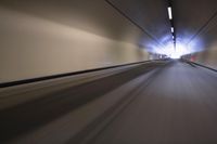 a long tunnel that leads into the distance with people inside and one is driving down the street