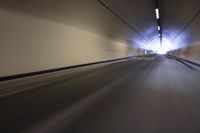 a long tunnel that leads into the distance with people inside and one is driving down the street
