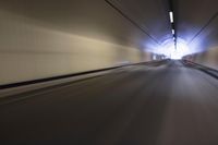 a long tunnel that leads into the distance with people inside and one is driving down the street