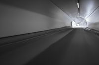 a long tunnel that leads into the distance with people inside and one is driving down the street
