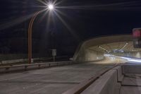 a car driving down the highway through a tunnel at night time and illuminated with some light