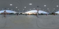 a fisheye image showing gas pumps at night time with one bike parked under a tent