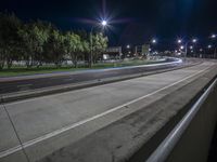 view of a deserted highway at night time with multiple lights on it and a long street