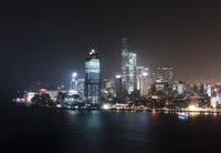 a city skyline lit up by lights from buildings above water and a dark sky beyond