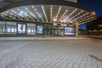 a large building with a big awning and windows lit up at night time with bright lights